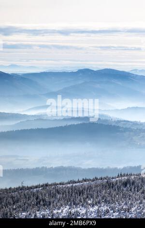 Paysage magique et brumeux d'hiver avec collines et vallées Banque D'Images