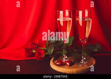 Verres de champagne, roses rouges, bonbons rouges - traditionnel romantique Saint Valentin arrière-plan de jour avec espace de copie. Banque D'Images