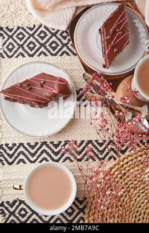 Cuisine esthétique festive pour la Saint-Valentin - gâteau au chocolat aux cerises, des morceaux de rhombus, des tasses de café parmi les décorations. Banque D'Images