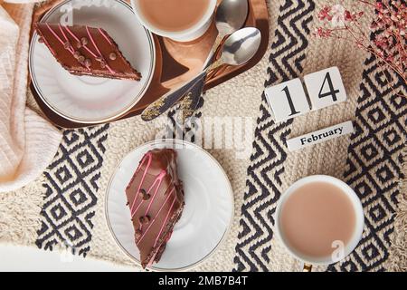 Petit déjeuner de fête délicat St Valentines avec des morceaux de gâteau au chocolat et aux cerises, des tasses de café et du texte du 14 février. Banque D'Images