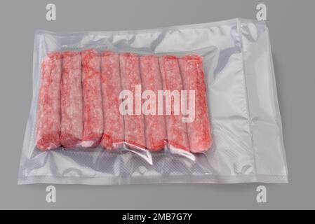 saucisse de dinde crue et de viande de porc emballée sous vide scellée pour la cuisson sous vide isolée sur fond gris dans la vue de dessus Banque D'Images