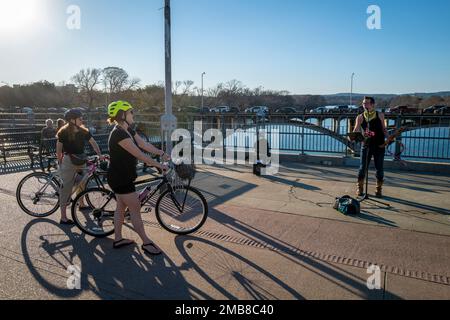 Les cyclistes s'arrêtent pour écouter le musicien de rue sur le pont piétonnier James D. Pfluger au-dessus du lac Ladybird, Austin, TX Banque D'Images