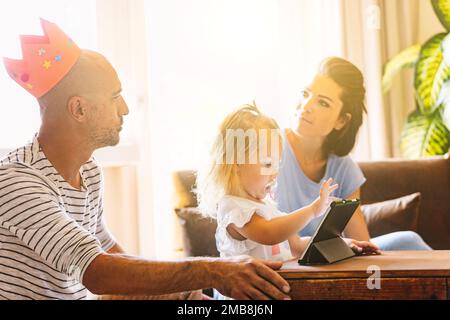 « Pensez-vous ce que je pense aussi ? » regardez entre la mère et le père pendant que l'enfant se divertit avec des applications éducatives sur la tablette avec eux Banque D'Images