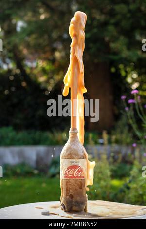 Des éclaboussures de Coca-Cola de la bouteille après l'ajout de bonbons Mentos. Banque D'Images