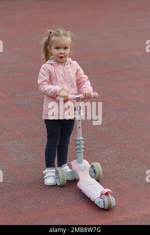 L'enfant aime monter son scooter de poussée Banque D'Images