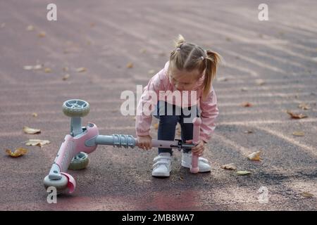 L'enfant aime monter son scooter de poussée Banque D'Images