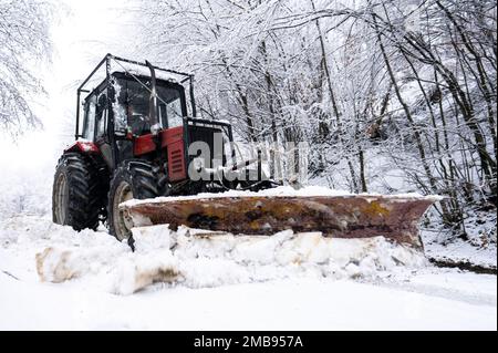 Un tracteur qui pele la neige d'une route de montagne dans les Carpates, Pologne. Banque D'Images