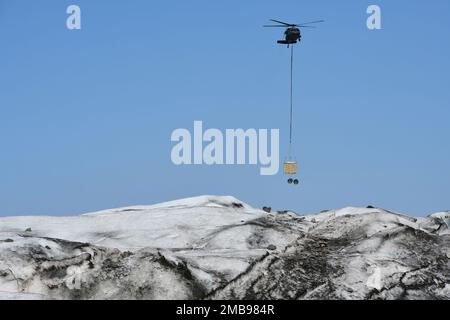 Un hélicoptère Black Hawk de la Garde nationale de l'Alaska transporte un conteneur pour l'entreposage de pièces d'aéronef récupérées sur Colony Glacier 13 juin 2022, dans le cadre de l'équipe qui travaille à récupérer les restes de 52 passagers et membres d'équipage, Et l'épave d'un avion Globemaster C-124 de la Force aérienne qui s'est écrasé le 22 novembre 1952, près du mont Gannet, en Alaska. Des soldats affectés à la Garde nationale de l'Armée de l'Alaska ont découvert les débris sur 10 juin 2012, au cours d'une mission d'entraînement en hélicoptère de routine de la Faucon noire sur le glacier de Colonia à près de 14 milles d'où l'avion s'est écrasé pour la première fois. (Photo de l'armée/John Pennell) Banque D'Images