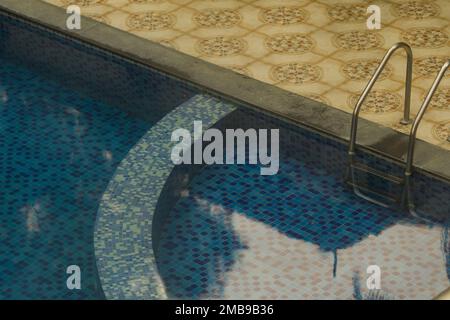 eau claire de la piscine pour enfants. le fond bleu de la piscine est visible. ladde d'acier inoxydable vu d'un côté de la piscine. Banque D'Images