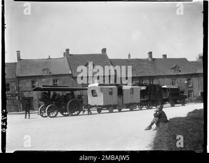 Stow-on-the-Wold, Cotswold, Gloucestershire, 1928. Un véhicule à vapeur tirant des caravanes tziganes à la Stow Horse Fair, devant une rangée de maisons, avec un jeune garçon regardant depuis le premier plan. Banque D'Images