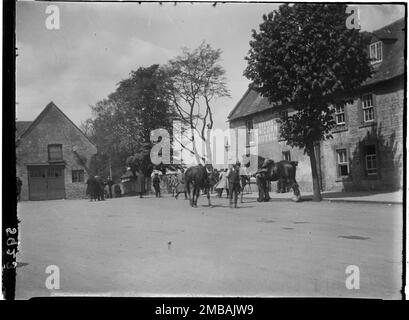 UNICORN Hotel, Sheep Street, Stow-on-the-Wold, Cotswold, Gloucestershire, 1928. Un groupe d'hommes et deux chevaux à une vente de chevaux tziganes sur la route principale de la foire du cheval Stow, rassemblés devant l'hôtel Unicorn. Banque D'Images