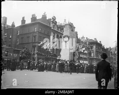 Cenotaph, Whitehall, Westminster, City of Westminster, Greater London Authority, 1919. Une foule s'est rassemblée autour du Cenotaph sur Whitehall pour les célébrations de la Journée de la paix avec des drapeaux et des banderoles sur les bâtiments derrière. Cette photo fait partie d'un groupe que le photographe a pris sur les 18th, 21st et amp ; 23rd juillet 1919, en enregistrant les décorations de paix qui avaient été érigées à Londres pour la Journée de la paix, 19th juillet 1919, à l'occasion de la fin de la guerre mondiale 1. Le cénotaphe illustré sur la photo a été construit à partir de bois et de plâtre et n'était prévu que pour une semaine pour la célébration de la Journée de la paix Banque D'Images