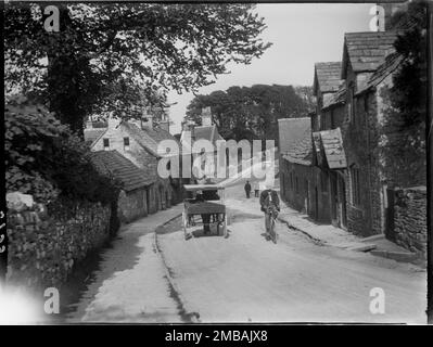 West Street, Kingston, Corfe Castle, Purbeck, Dorset, 1927. En regardant vers l'est le long de West Street à Kingston, montrant une voiturette tirée par des chevaux et un cycliste passant les numéros 5 et 7 à droite du premier plan. Banque D'Images