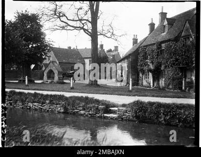 The Square, Lower Slaughter, Cotswold, Gloucestershire, 1928. En regardant de l'autre côté de la rivière Eye vers la fontaine et les maisons sur la place, avec des chevaux et des personnes en face. Banque D'Images