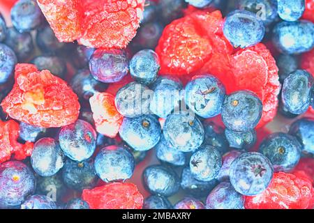 Bleuets et framboises frais congelés, gros plan. Vue rapprochée des baies et framboises. Texture des baies congelées. Conception plate, vue de dessus. Hé Banque D'Images