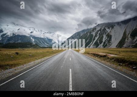 Hooker Track Road près du Mont Cook dans l'île du Sud de la Nouvelle-Zélande menant vers des montagnes enneigées avec des nuages sombres au-dessus Banque D'Images