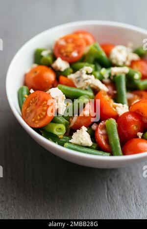 Bol avec une salade de haricots verts et de tomates cerises et du fromage feta vegan maison. Banque D'Images