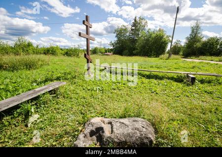 Pierre-sledovik et culte croix sur le côté de la route. Village de Pozdyshevo, région d'Arkhangelsk Banque D'Images