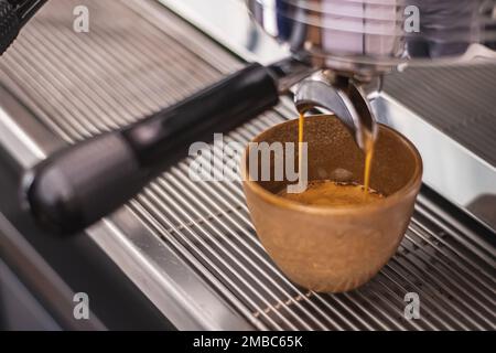 Préparation du café avec une machine à café au bar, le café est versé dans une tasse en céramique, gros plan Banque D'Images