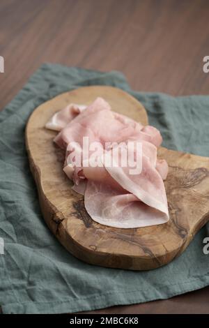 Fines tranches de prosciutto cotto sur panneau de bois d'olive, peu profond foyer Banque D'Images