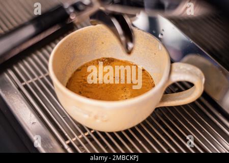 Préparation du café avec une machine à café au bar, le café est versé dans une tasse en céramique, gros plan Banque D'Images