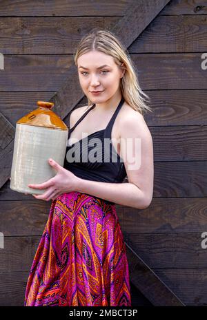 Par une journée d'hiver très froide à Dundee, une belle et à la mode femme Hayleigh Young tient un flagon de bière des années 1800 près du navire RRS Discovery, en Écosse Banque D'Images