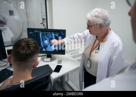 Les employés du service de diagnostic, les femmes et les hommes âgés, effectuent la procédure d'IRM Banque D'Images