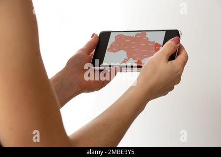 La jeune fille tient un téléphone avec une carte des alarmes en Ukraine, un avertissement sur les missiles dans le ciel sur toute l'Ukraine, une guerre en Ukraine, une attaque de Banque D'Images