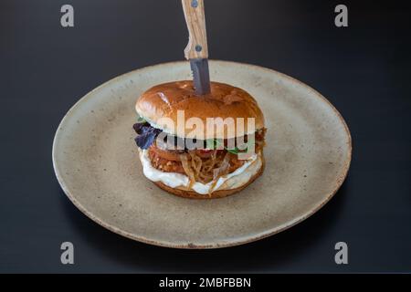 Hamburger hamburger cheeseburger avec fromage de poulet de porc sur une assiette et un couteau bloqué. Banque D'Images