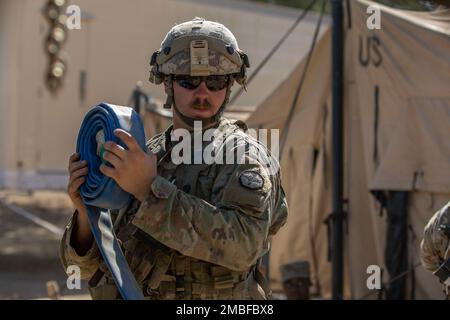 ÉTATS-UNIS Bryan Dakota, spécialiste du traitement de l'eau affecté à la compagnie Quartermaster 651st basée à Casper, Wyoming, enroule un tuyau utilisé pour transporter l'eau des sacs utilisés pour une tente de douche lors de l'exercice d'entraînement de soutien au combat 91-22-01 à fort Hunter Liggett, Californie, 15 juin. Le Dakota est spécialiste du traitement de l'eau dans les réserves de l'Armée de terre depuis plus de six ans et travaille également comme opérateur de grue civile. Banque D'Images