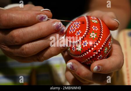 Berlin, Allemagne. 20th janvier 2023. Helene Herberg, de l'association 'Landurlaub in Sachsen', teinte un œuf avec une douille et une cire rouge au stand de la salle d'exposition de Saxe pendant la semaine verte internationale (IGW). Le plus grand salon mondial de l'alimentation, de l'agriculture et de l'horticulture existe depuis 1926. Depuis 1996, le salon d'information et de commerce « Heim-Tier & Pflanze » s'inscrit également dans son cadre. L'édition de cette année se termine le 29.01.2023. Crédit : Soeren Stache/dpa/Alay Live News Banque D'Images