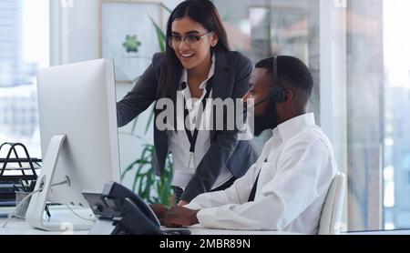 Cela devrait fonctionner si vous cliquez ici. une jeune femme d'affaires qui aide un collègue dans un centre d'appels. Banque D'Images