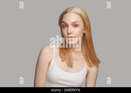 Parfaite femme modèle avec la coiffure blonde et le maquillage naturel posant sur fond blanc Banque D'Images