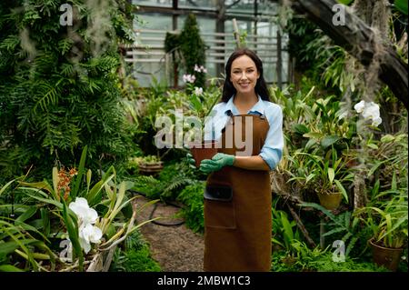 Portrait de jeune femme jardinier tenant une plante en pot Banque D'Images