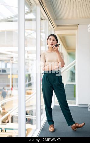 Veuillez m'appeler une fois que vous avez reçu ce message. une jeune femme d'affaires utilisant un téléphone portable dans un bureau. Banque D'Images