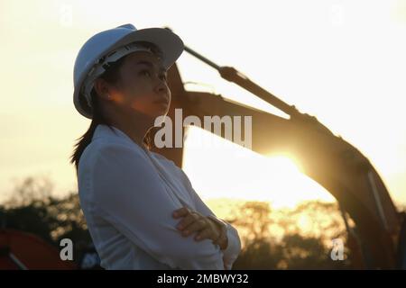 Portrait d'un ingénieur asiatique portant un casque blanc travaillant et inspectant sur le lieu de travail. Ingénieur civil vérifiant après les travaux sur le chantier pendant le su Banque D'Images
