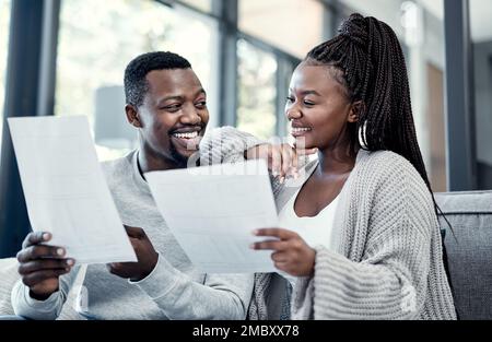 Regardez le miel, les prêts tous payés. un jeune couple qui passe par la paperasse à la maison. Banque D'Images