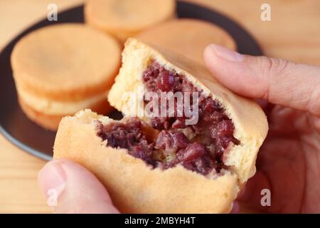 Gros plan de la main découpage savoureux de la pâte de haricots azuki japonais dessert rempli appelé Imagawayaki ou Obanyaki Banque D'Images