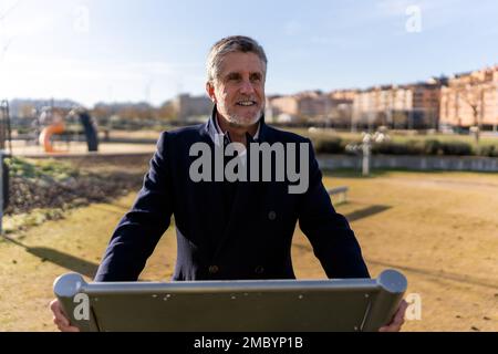 Homme d'affaires mûr et confiant, habillé, souriant et regardant loin tout en se tenant contre le paysage urbain Banque D'Images