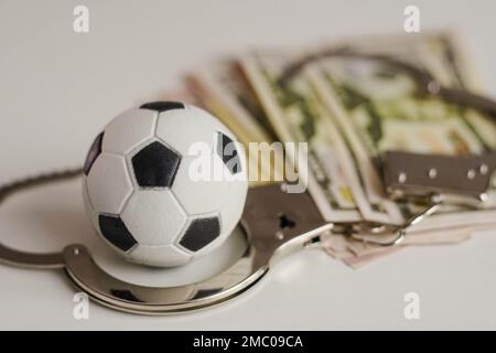 Ballon de football avec argent et menottes. Corruption dans le football, les jeux d'argent et la corruption dans le sport. Banque D'Images