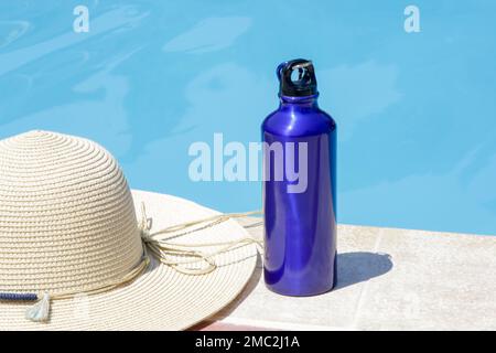 Bouteille bleue légère en aluminium réutilisable au bord de la piscine Banque D'Images