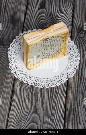 Miel en nid d'abeille dans un cadre en bois. Sur les planches de pin noir. Sur fond noir. Banque D'Images