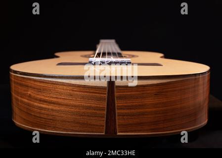 Guitare classique isolée sur fond noir, vue du bas. Magnifique bois brésilien - Pau Ferro à l'arrière et épicéa au sommet. Banque D'Images