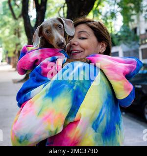 Femme latine tenant son chien. Les deux sont habillés comme l'appareil photo. Banque D'Images