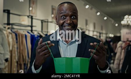 Gros plan d'âge moyen Africain américain homme d'affaires homme regardant à l'intérieur sac shopping heureux avec paquet cadeau joie avec cadeau recevoir commande Banque D'Images