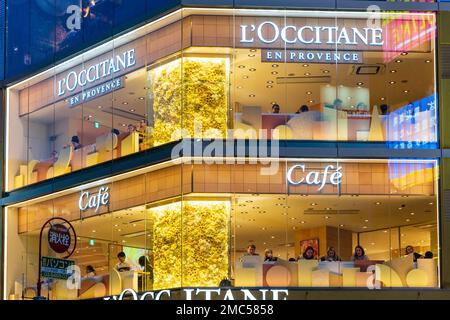 Tokyo, Shibuya, soir. De l'extérieur L'Occitane café, en regardant par les fenêtres en verre de l'Ouest surtout diners assis au bar à l'extérieur. Banque D'Images
