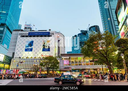 Taxi au-dessus de la célèbre traversée de brouille à Shibuya avec des foules de personnes attendant de traverser la route à l'extérieur de la gare JR. Soirée. Banque D'Images