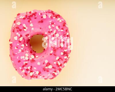 Beignet rose sucré avec des saupoudrés multicolores sur fond jaune. Dessert sucré coloré Banque D'Images