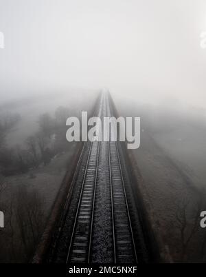 Un paysage aérien directement au-dessus des voies de chemin de fer sur un vieux viaduc qui disparaît dans le brouillard au loin avec l'espace de copie Banque D'Images