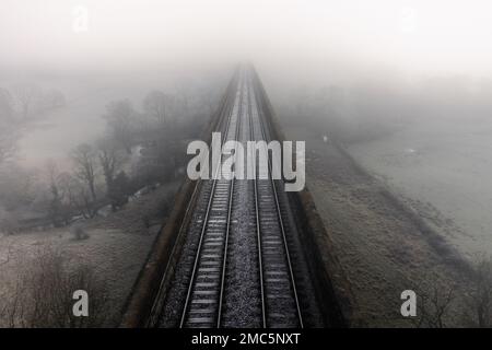 Un paysage aérien directement au-dessus des voies de chemin de fer sur un vieux viaduc qui disparaît dans le brouillard au loin avec l'espace de copie Banque D'Images